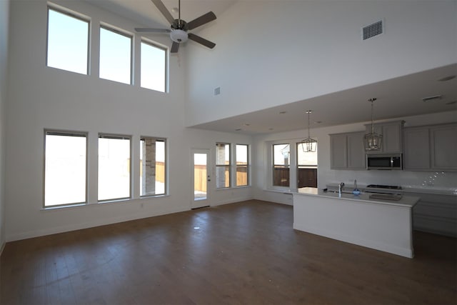 kitchen featuring dark wood-style floors, stainless steel microwave, open floor plan, gray cabinets, and light countertops