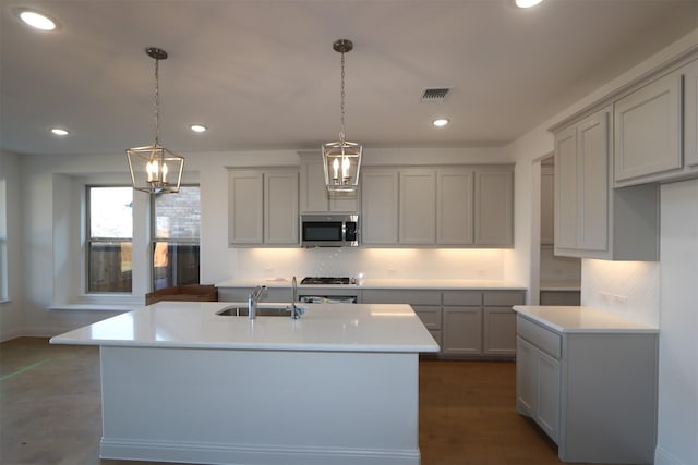 kitchen featuring light countertops, stainless steel microwave, a sink, and pendant lighting