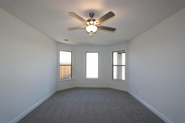 spare room with ceiling fan, baseboards, visible vents, and dark carpet