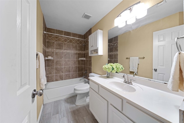 full bathroom with toilet, vanity, wood-type flooring, and tiled shower / bath