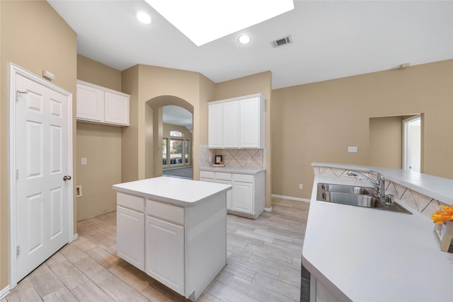 kitchen featuring a center island, white cabinetry, and sink