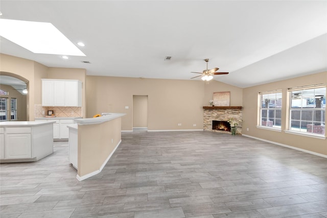 kitchen featuring white cabinetry, ceiling fan, tasteful backsplash, vaulted ceiling with skylight, and a kitchen island