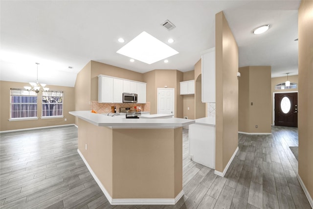 kitchen with stainless steel appliances, light hardwood / wood-style flooring, a center island, white cabinetry, and hanging light fixtures