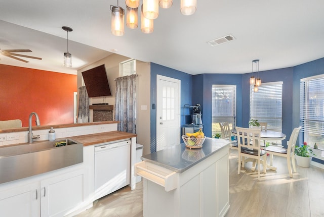 kitchen with white dishwasher, decorative light fixtures, white cabinetry, and sink