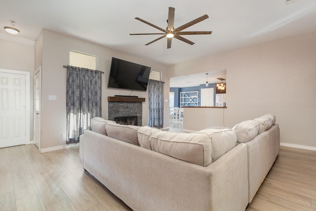 living room featuring a fireplace, ceiling fan, and light hardwood / wood-style flooring