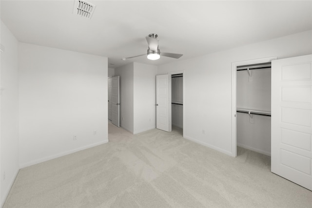 unfurnished bedroom featuring light carpet, two closets, and ceiling fan