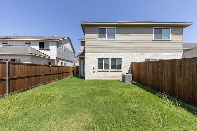 rear view of property featuring a lawn and central air condition unit