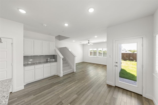 kitchen featuring ceiling fan, tasteful backsplash, light stone countertops, white cabinets, and light wood-type flooring