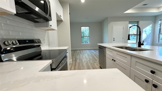 kitchen featuring stainless steel appliances, white cabinetry, light hardwood / wood-style floors, and sink