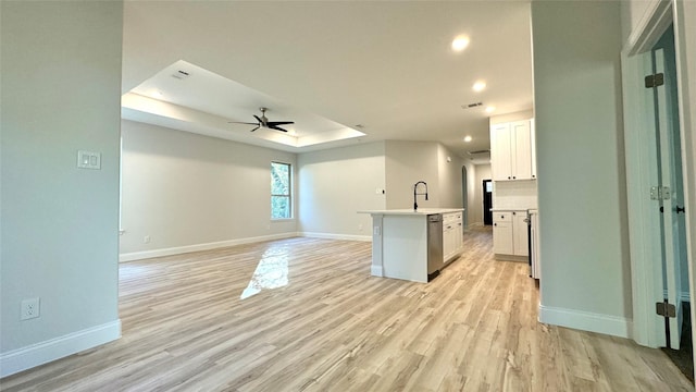 kitchen featuring a center island with sink, light wood-type flooring, white cabinetry, and a tray ceiling