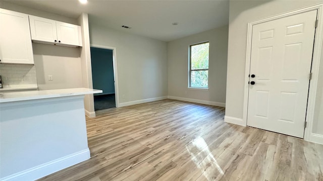 kitchen featuring white cabinetry, backsplash, and light hardwood / wood-style flooring