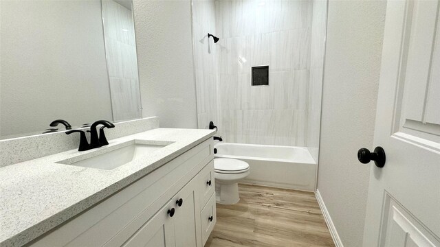 full bathroom featuring vanity, wood-type flooring, tiled shower / bath combo, and toilet