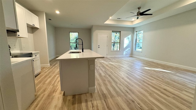 kitchen with a center island with sink, light hardwood / wood-style floors, white cabinetry, and sink