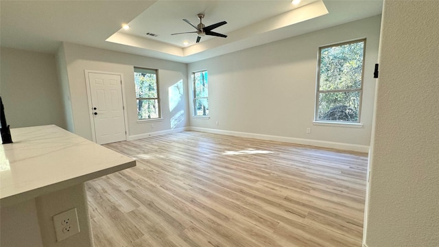 interior space featuring a tray ceiling, light hardwood / wood-style flooring, and ceiling fan