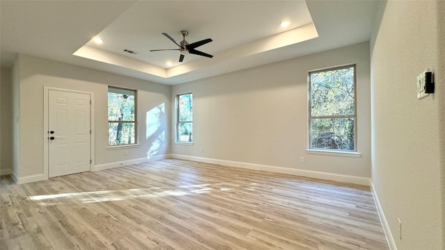 spare room featuring ceiling fan, light hardwood / wood-style flooring, and a tray ceiling