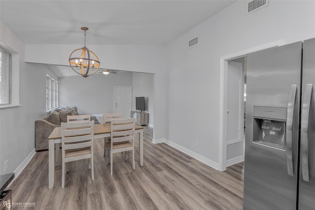 dining room with a chandelier, hardwood / wood-style flooring, and vaulted ceiling