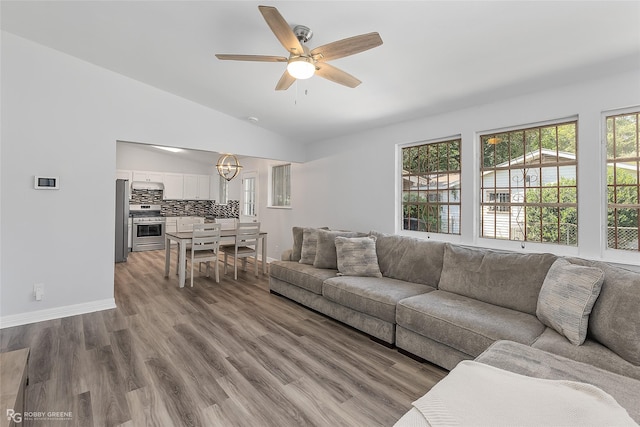 living room featuring hardwood / wood-style floors, ceiling fan with notable chandelier, plenty of natural light, and lofted ceiling