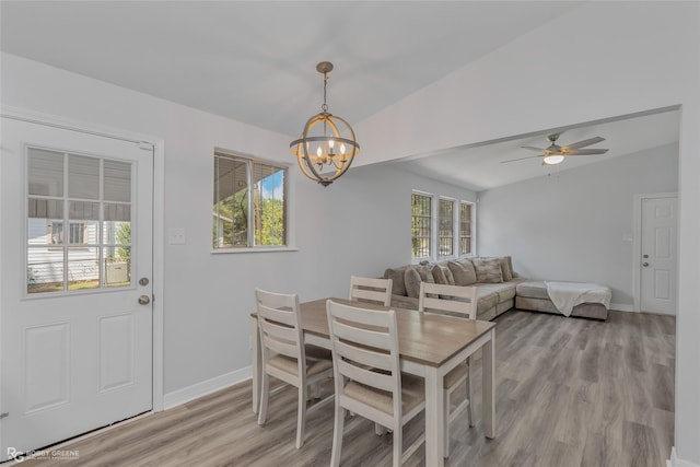 dining area featuring ceiling fan with notable chandelier, light hardwood / wood-style floors, and vaulted ceiling