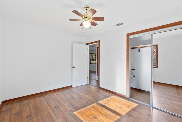 unfurnished bedroom featuring hardwood / wood-style floors, a closet, and ceiling fan