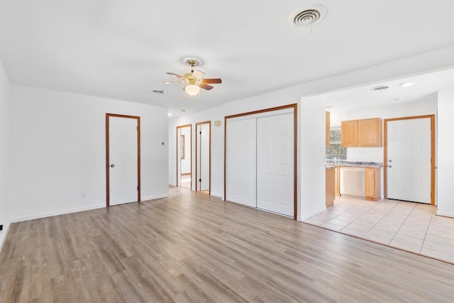 unfurnished bedroom featuring connected bathroom, ceiling fan, and light wood-type flooring