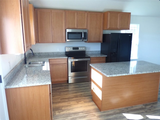 kitchen with light stone counters, light wood-type flooring, sink, and appliances with stainless steel finishes