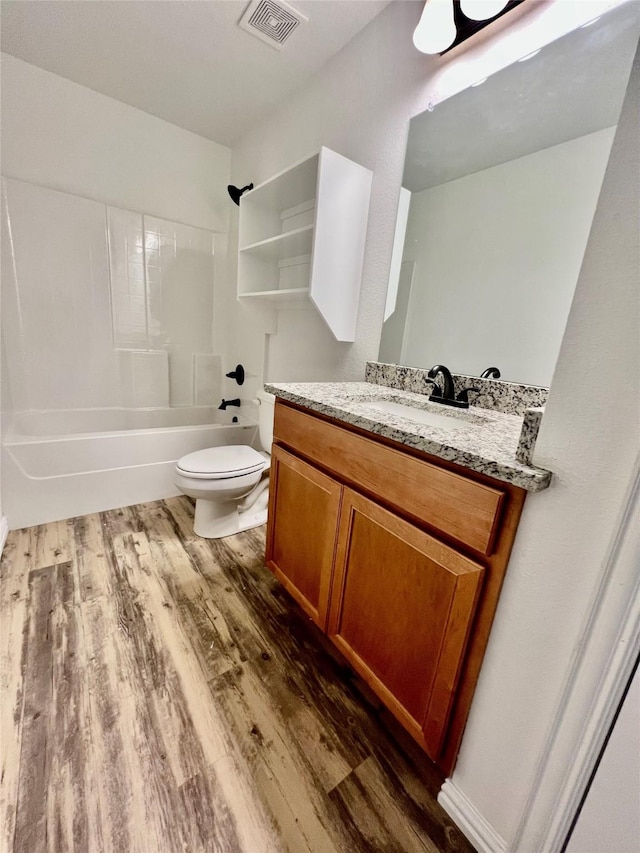 full bathroom with washtub / shower combination, vanity, hardwood / wood-style flooring, and toilet