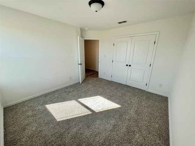 unfurnished bedroom featuring dark carpet and a closet