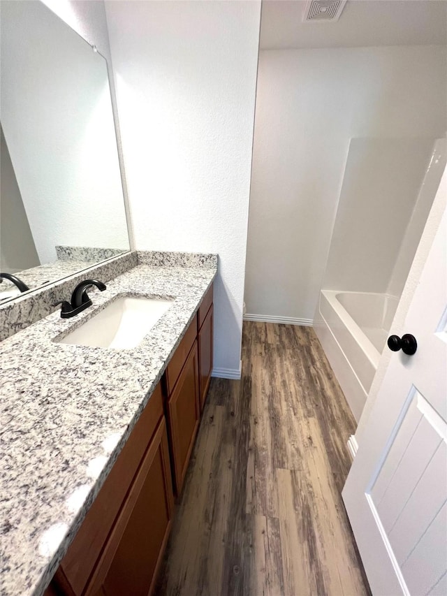 bathroom with hardwood / wood-style floors, vanity, and a washtub