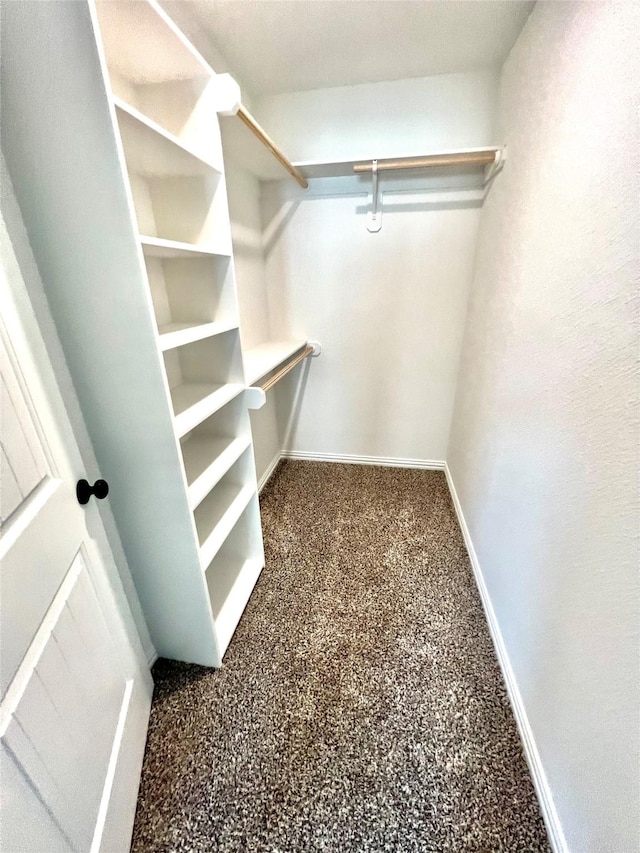 spacious closet featuring dark colored carpet