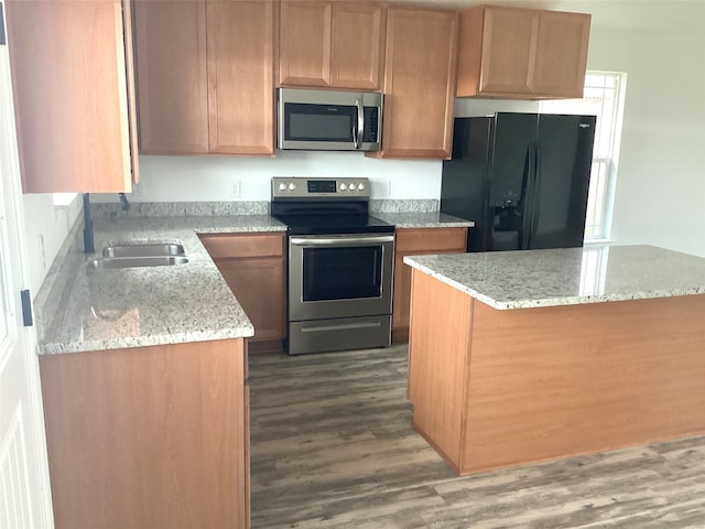 kitchen with dark hardwood / wood-style flooring, light stone counters, sink, and appliances with stainless steel finishes