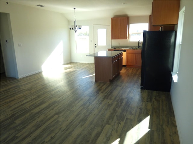 kitchen with a center island, hanging light fixtures, dark wood-type flooring, a chandelier, and black refrigerator