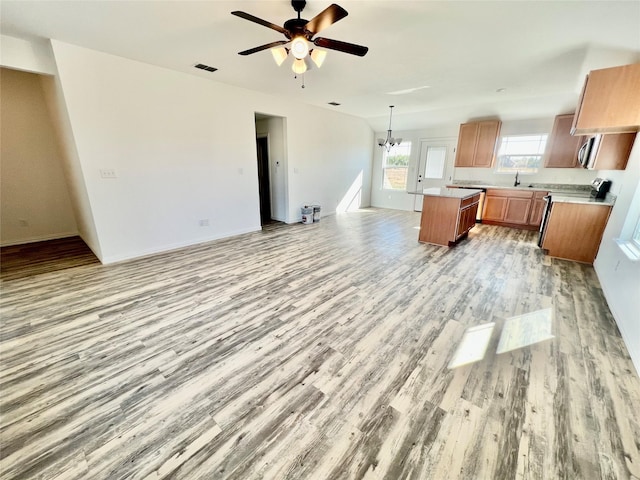 kitchen with sink, hanging light fixtures, light hardwood / wood-style floors, a kitchen island, and ceiling fan with notable chandelier