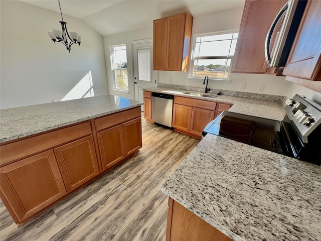 kitchen featuring sink, light hardwood / wood-style flooring, vaulted ceiling, decorative light fixtures, and appliances with stainless steel finishes