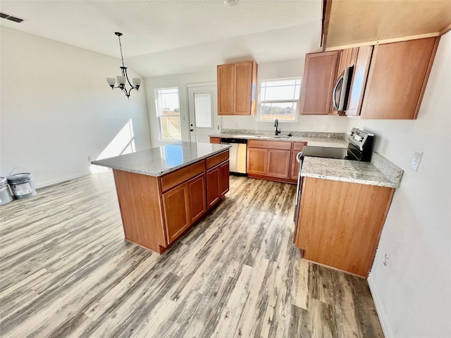 kitchen featuring stainless steel appliances, light hardwood / wood-style flooring, lofted ceiling, decorative light fixtures, and a kitchen island