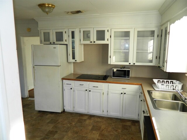 kitchen with black electric stovetop, ornamental molding, sink, white cabinets, and white fridge