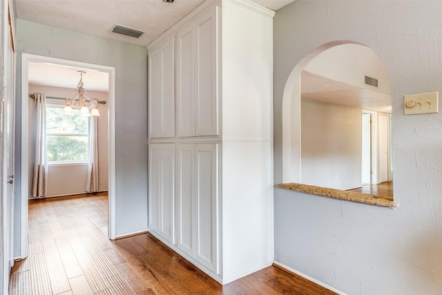 hall with an inviting chandelier and light hardwood / wood-style flooring