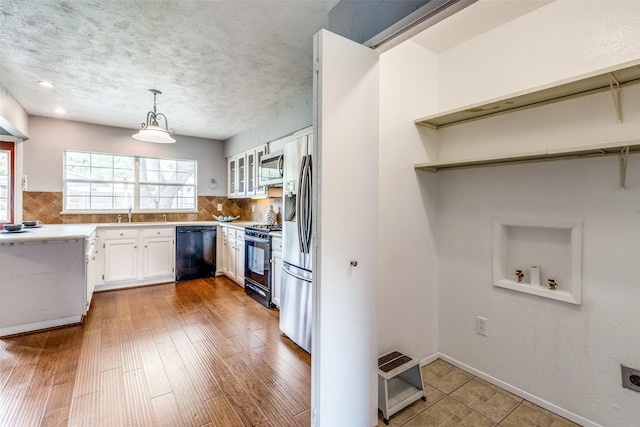 kitchen featuring pendant lighting, black appliances, decorative backsplash, white cabinetry, and wood-type flooring