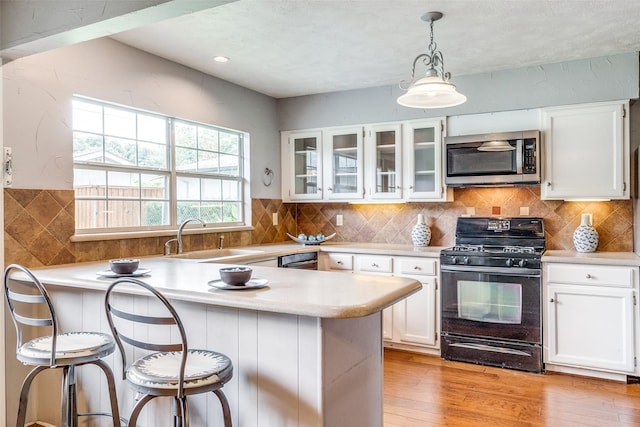 kitchen featuring a breakfast bar, sink, black appliances, light hardwood / wood-style flooring, and white cabinets