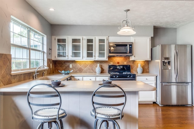 kitchen featuring stainless steel appliances, dark wood-type flooring, sink, white cabinets, and a breakfast bar area