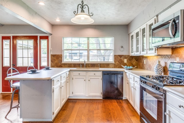 kitchen with white cabinetry, stainless steel appliances, light hardwood / wood-style flooring, decorative light fixtures, and a kitchen bar