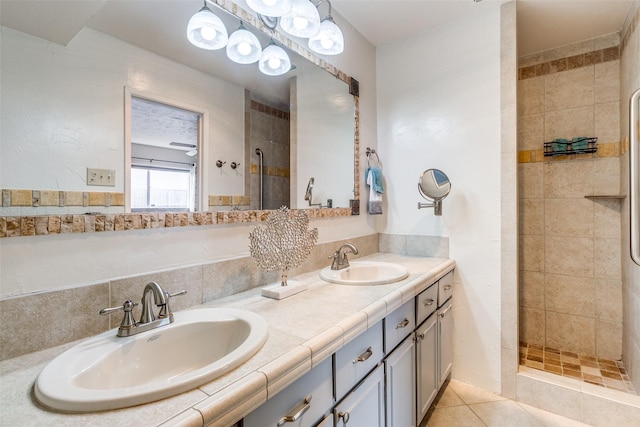 bathroom with tile patterned flooring, vanity, and a tile shower