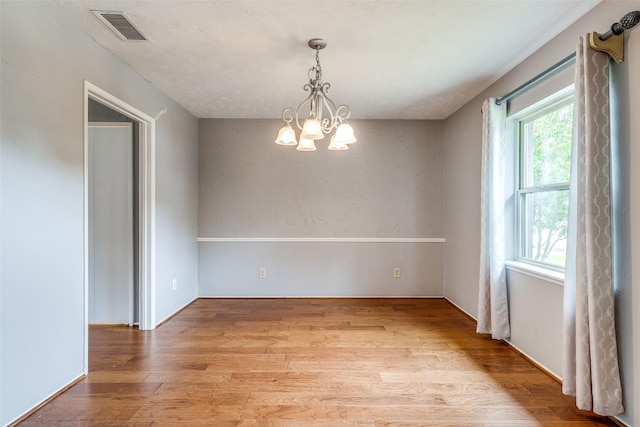 unfurnished dining area with a notable chandelier and light wood-type flooring