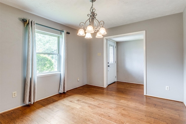 empty room with light hardwood / wood-style floors and a notable chandelier