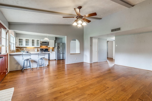 unfurnished living room with vaulted ceiling with beams, ceiling fan, light hardwood / wood-style flooring, and sink