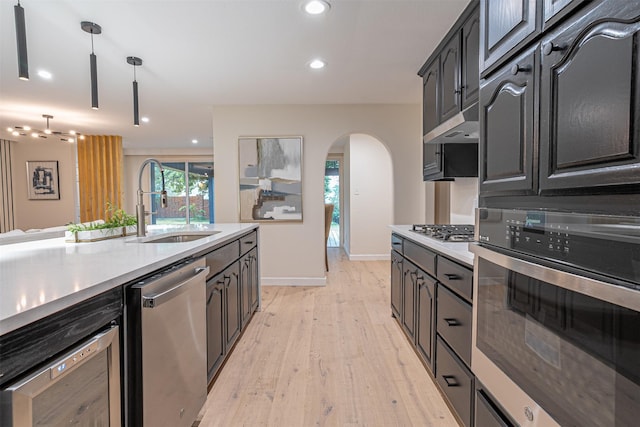 kitchen with pendant lighting, light hardwood / wood-style floors, sink, and appliances with stainless steel finishes