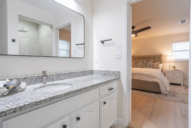 bathroom featuring a shower, hardwood / wood-style floors, vanity, and ceiling fan