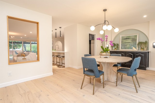 dining room with light hardwood / wood-style floors and an inviting chandelier