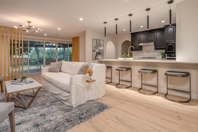 living room with light wood-type flooring and an inviting chandelier