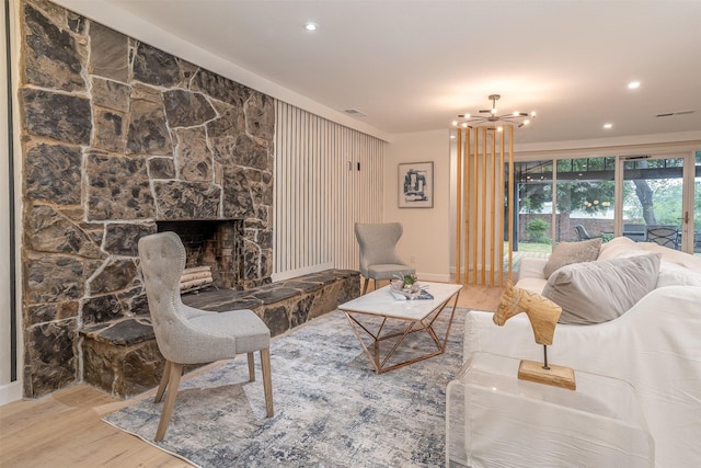 living room with hardwood / wood-style flooring, a notable chandelier, and a stone fireplace