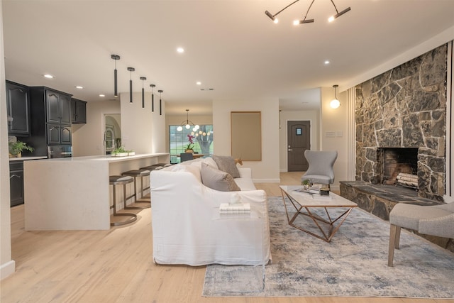 living room featuring an inviting chandelier, a fireplace, and light hardwood / wood-style flooring